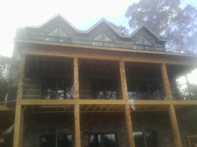 Dormers and porch framing on a large log home under construction — Roof Coating work by our crew in Edison
