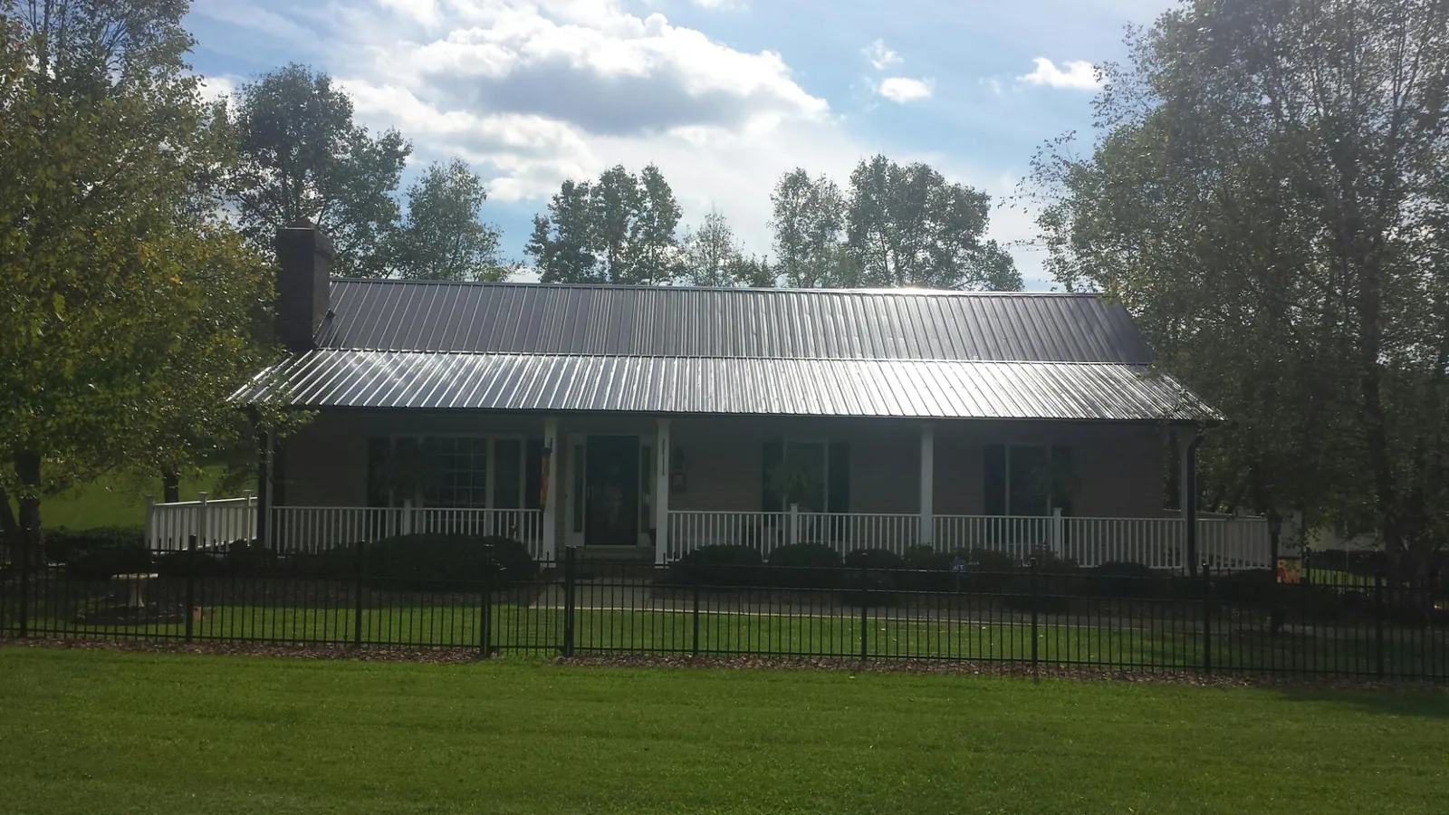 Gray metal roof on a brick ranch with a full width front porch — Gutter Guard Installation work by our crew in Edison
